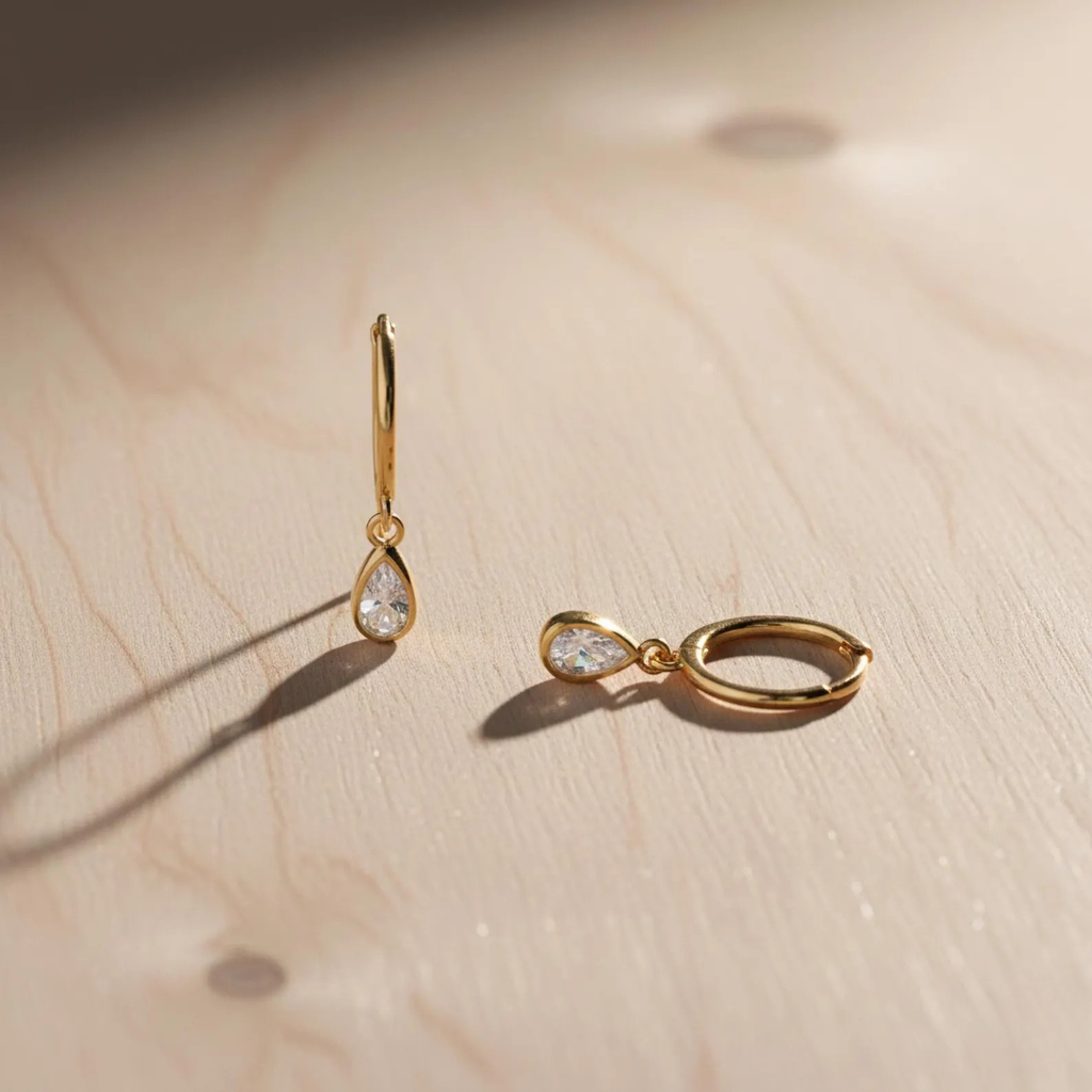 Sterling silver teardrop huggie earrings with dainty CZ stones, Luxe Treasures jewelry, close-up view of elegant hoop earrings.