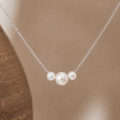 Dainty gold necklace with three freshwater pearls, minimalist layering jewelry by Luxe Treasures, displayed on a neutral background.
