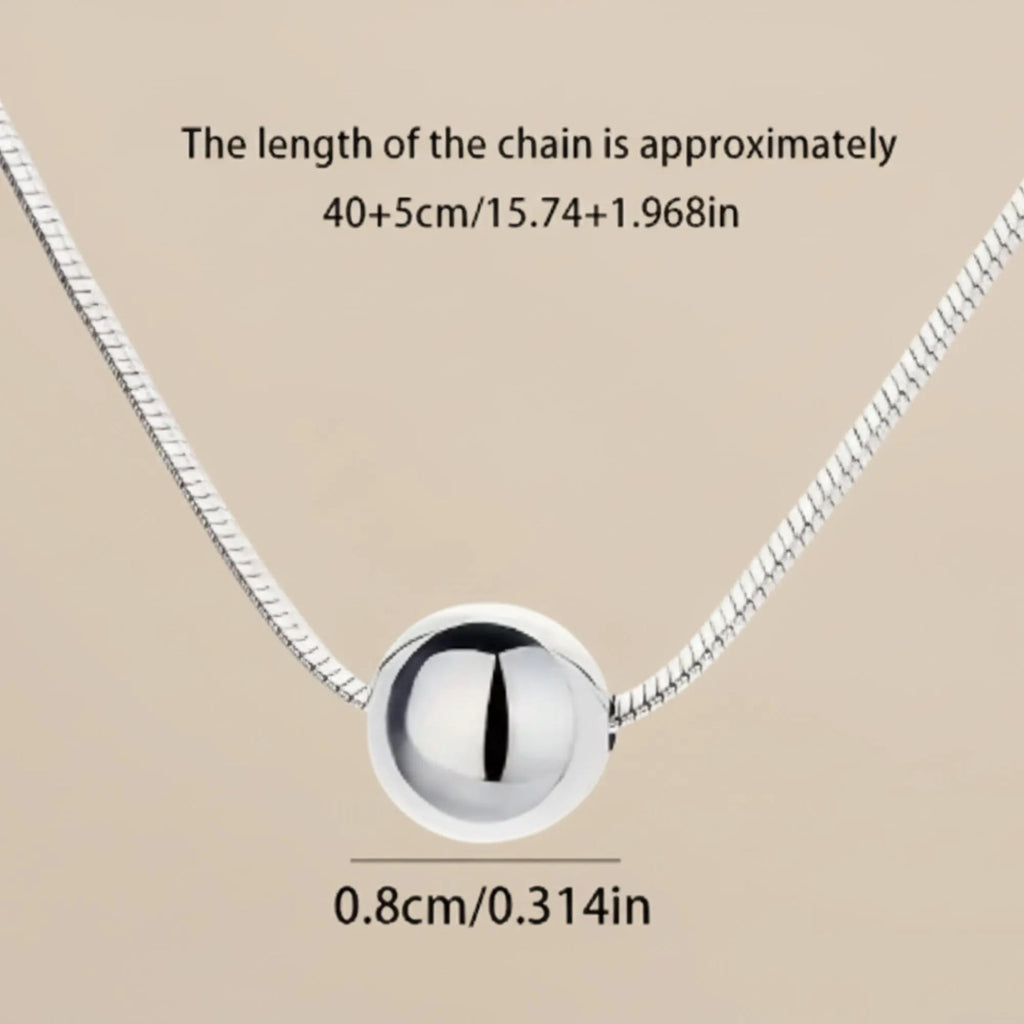 Sterling silver ball necklace on snake bone chain, minimalist boho jewelry by Luxe Treasures, close-up view of chain and pendant.